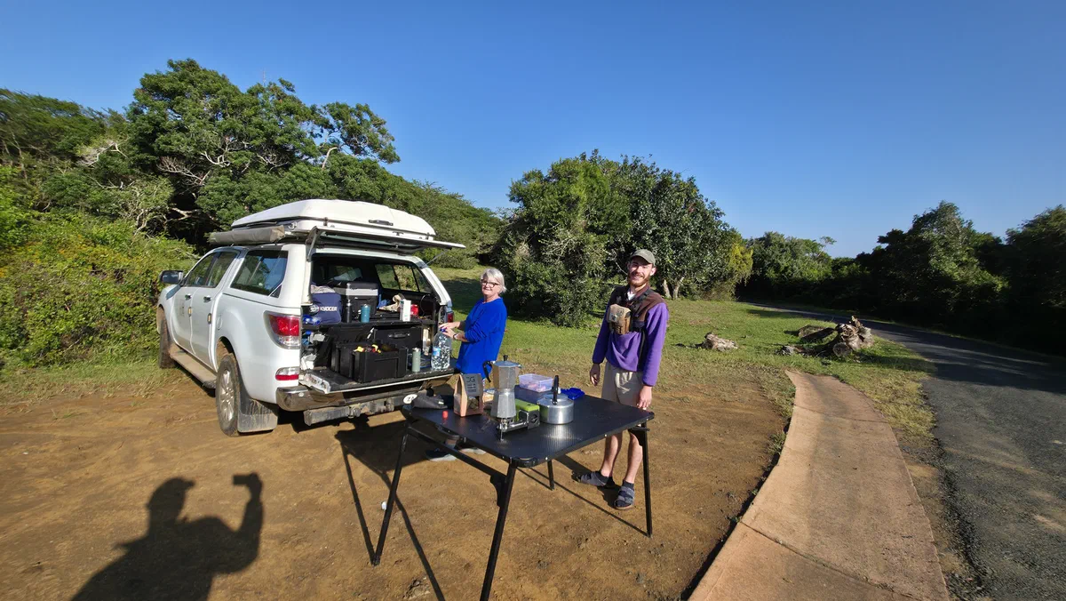 Guests at a fold-out breakfast table beside the vehicle on a sunny morning