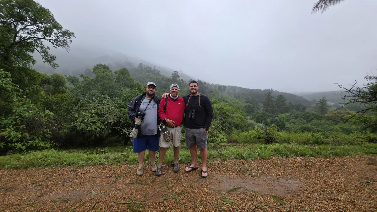 Three photographers with cameras and binoculars on a misty morning